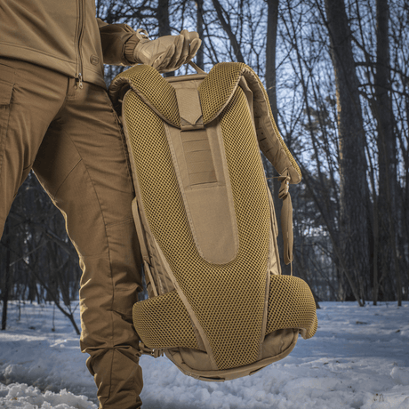 Person holder M-Tac Rygsæk Gen.II Elite Large i sneklædt skov, viser ergonomisk design og slidstærke materialer.