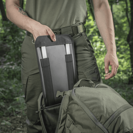 M-Tac Rygsæk Gen.II Elite Large med person der tager noget ud af rygsækken i skovmiljø.
