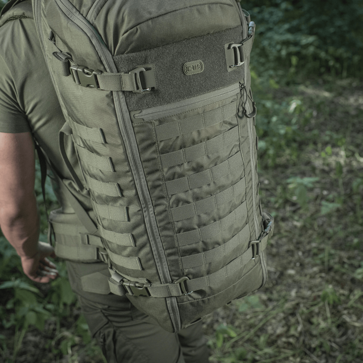 Person iført M-Tac Rygsæk Gen.II Elite Large i naturen, viser rygsækkens holdbare Cordura design og rummelige opbevaringsmuligheder.
