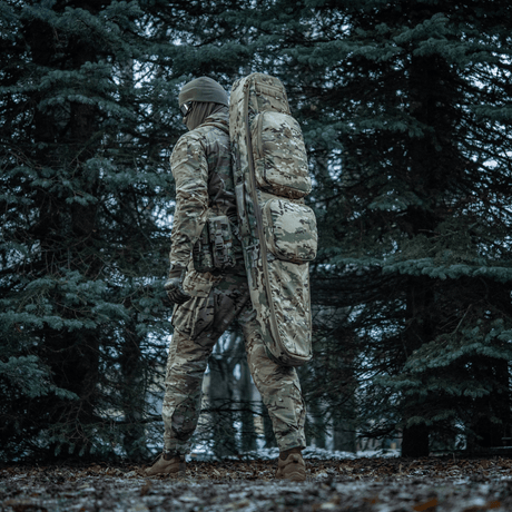 Person i skog med M-Tac Gun Backpack Case 125 cm Gen.II Elite, designad för säker vapentransport, camouflage