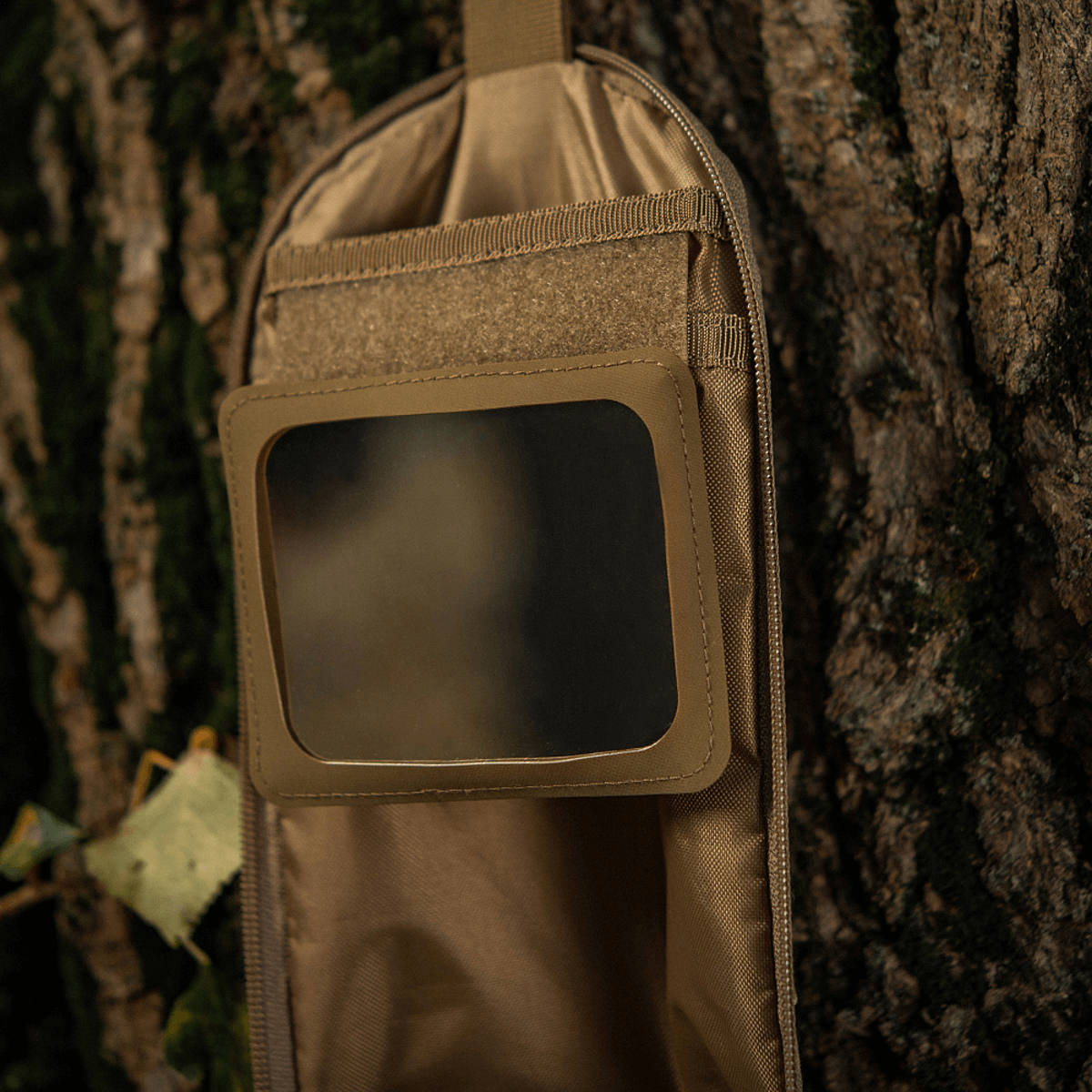 M-Tac Toilettaske Elite Gen.II hængende ved træ, brugt til opbevaring af hygiejneartikler som barbermaskine, tandbørste og småting.