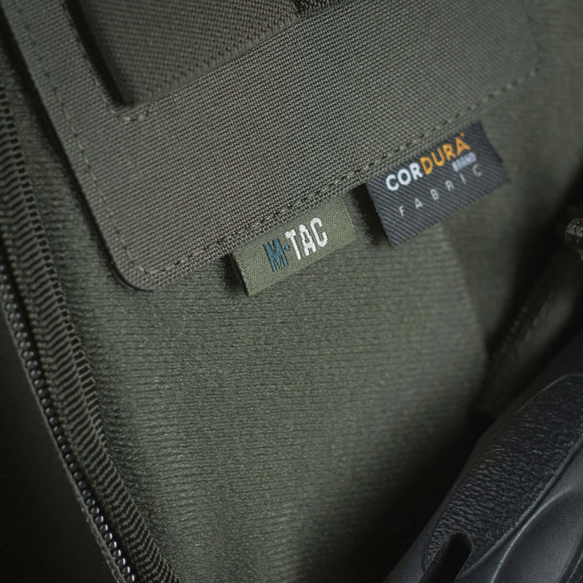 Close-up of M-Tac Double Mag Pouch Hook Backed Magazine with Cordura fabric label and Velcro attachment details in dark green.