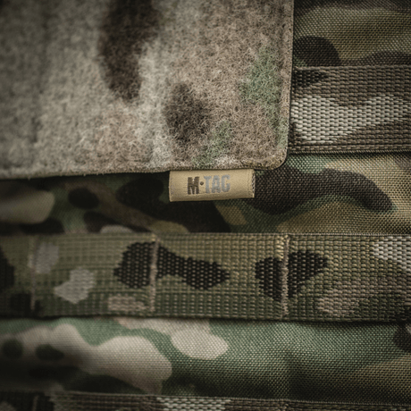 M-Tac panel för patches på MOLLE 120x85 med hook & loop-yta och plastbas, fäst på camouflagemönstrat MOLLE-system