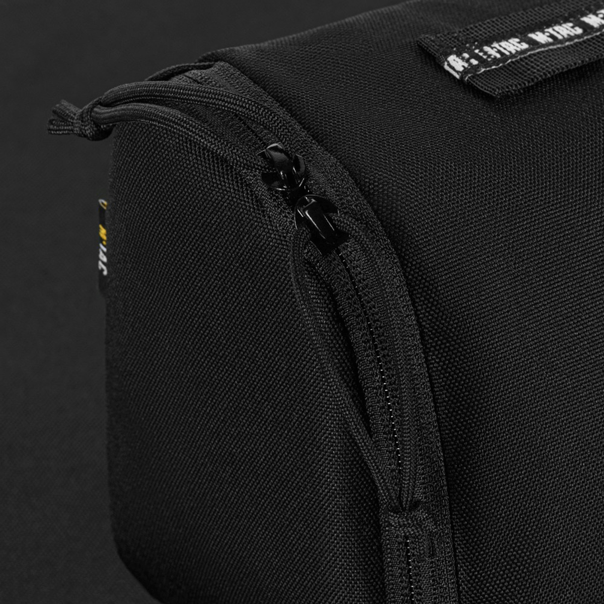 Detaljeret nærbillede af sort M-Tac Toilettaske med lynlås, vandafvisende og slidstærk 600D polyester materiale.