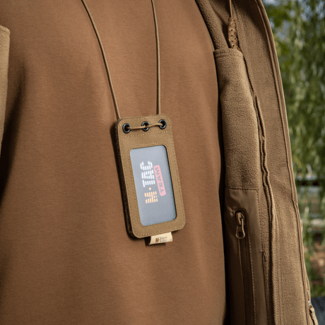 M-Tac taktisk ID-korthållare med snöre i Cordura-material och transparent fönster, bärs runt halsen på en person, lämplig för taktisk användning.