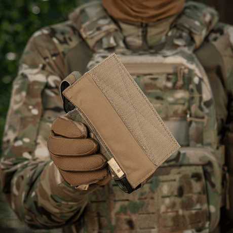 M-Tac Tourniquet Pouch Elastisk VELCRO Gen.II i kamouflerad miljö, hålls av en person med taktisk utrustning