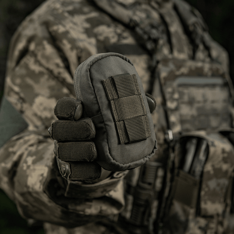 M-Tac PC Utility Pouch Elite i camouflagedräkt, Cordura-material med MOLLE-interface, visas i militär miljö. Taktisk väska för förvaring