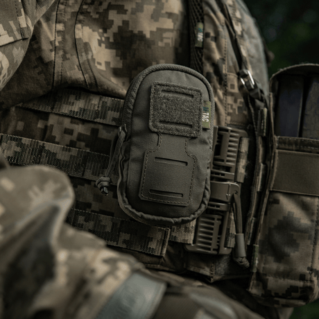 Soldat med M-Tac PC Utility Pouch Elite monterad på MOLLE-system, mångsidig Cordura-väska för småsaker i taktisk miljö.