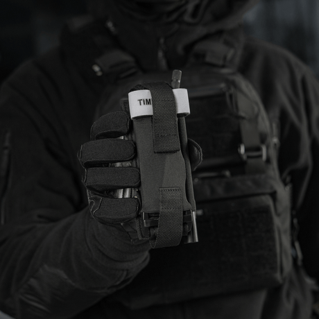Taktisk operatör håller M-Tac Elastisk Tourniquet Pouch Molle Gen.III i Cordura Squadron med bred elastik och blixtsnabb åtkomst.