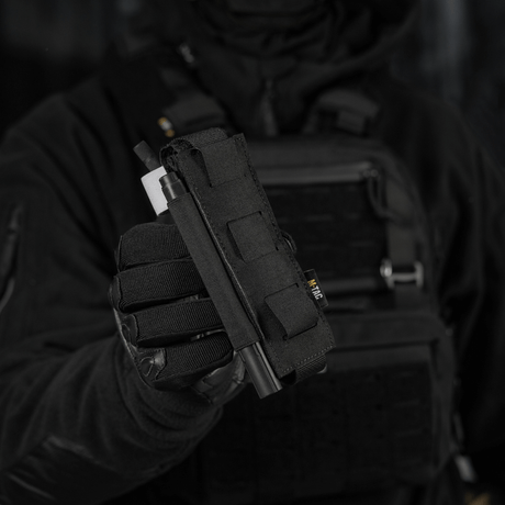 M-Tac Elastisk Tourniquet Pouch Molle Gen.III i användning, hålls av en person i taktikutrustning, framhäver funktionalitet och design.