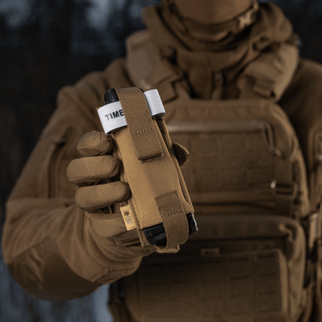 M-Tac elastisk tourniquetficka Molle Gen.III i bruk i fält, framhäver snabb åtkomst och säker fästning av tourniquet.