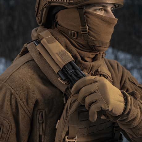Person i taktiska kläder med M-Tac elastisk tourniquetficka Molle Gen.III monterad på axeln i vinterlandskap