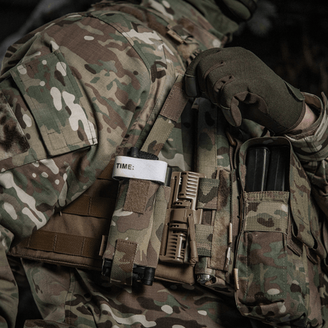 M-Tac elastisk tourniquetficka Molle Gen.III fäst på taktisk väst med tourniquet och extra utrustning i militärt område.