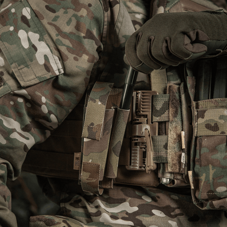 M-Tac elastisk tourniquetficka Molle Gen.III i bruk, monterad på en militärväst i kamouflagemönster med bred elastik för säker fästning.