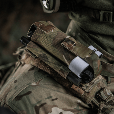M-Tac elastisk tourniquetficka Molle Gen.III fäst på militärväst i kamouflage, säkerställer enkel åtkomst till C-A-T tourniquet.