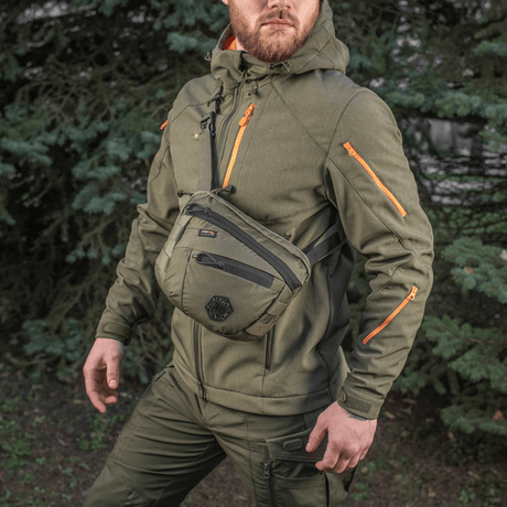 M-Tac Sphaera Hex Hardsling-väska Gen.II Elite på en man klädd i militärgrönt i naturen.