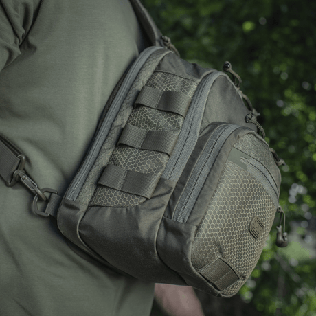 M‑Tac Cross Bag Elite Hex slingpack i Cordura 500, sedd på axeln i gröna omgivningar, perfekt för vardagsbruk och taktisk utrustning. 5 liter.