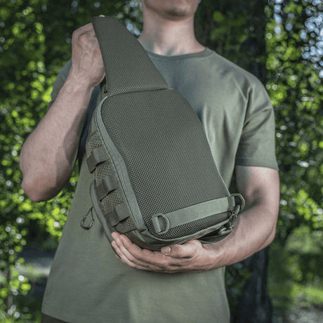 Man bär M‑Tac Cross Bag Elite Hex, en kompakt väska i Cordura 500, idealisk för vardagsbruk och taktisk utrustning.
