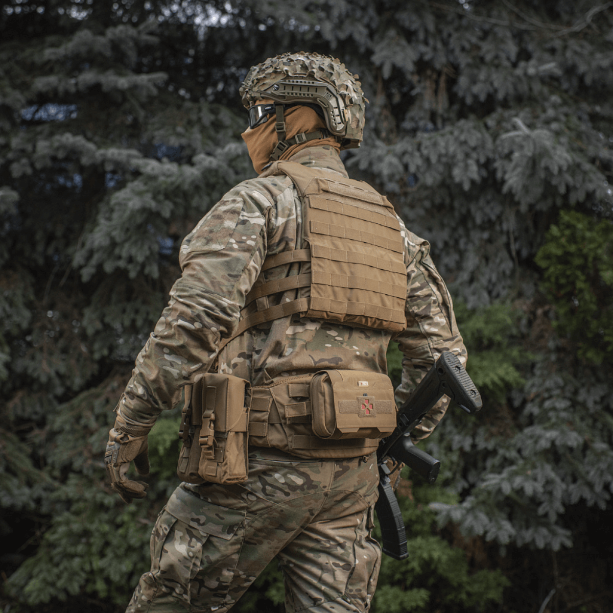 Soldat iført M‑Tac Plate Carrier Cuirass QRS Gen.II med hurtigudløsningssystem i skovmiljø. Taktisk udstyr til moderne operationer.