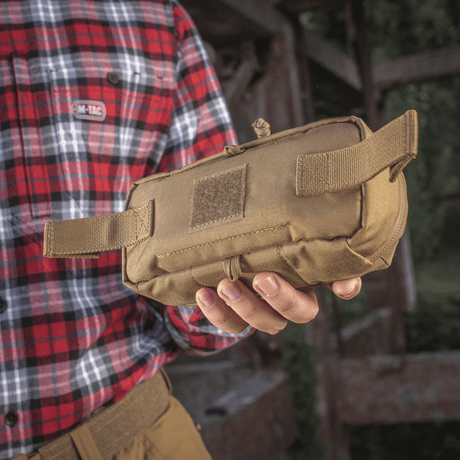 M-Tac Horizontal Medical Pouch Elite i en persons hand, hållbart fältkit för första hjälpen med inre organizer och vattentät dragkedja.
