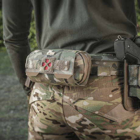 M-Tac Horizontal Medical Pouch Elite monterad på camouflagedräkt i fält, idealisk för första hjälpen med vattentät dragkedja och organizer.