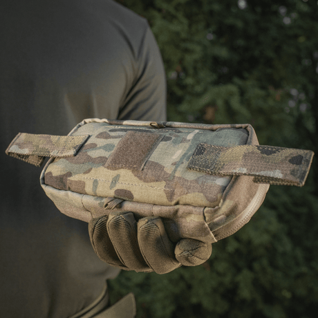 Person håller M-Tac Horizontal Medical Pouch Elite i camouflage, idealisk för fältbruk och första hjälpen, med robust design och vattentät dragkedja.