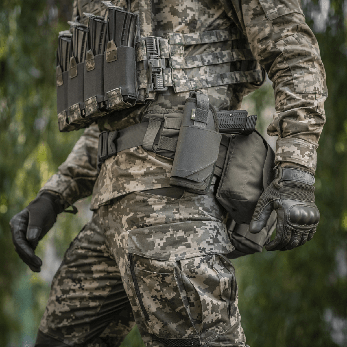 M-Tac Universal Taktisk Hylster Elite Venstre i brug på camouflageuniform med MOLLE-interface og justerbar strop til pistolsikring.