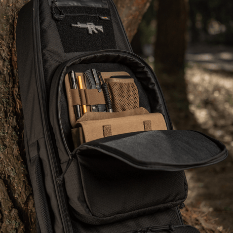 M-Tac Gun Backpack Case 105 cm Elite Hex i skogen, öppen med fack för tillbehör.