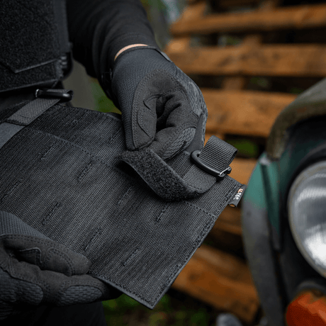 En person justerar M‑Tac Front Panel för Cuirass QRS med Woojin-krokar och Velcro, tillverkad av Cordura 500D, för militärt bruk.