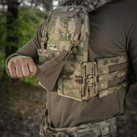 M‑Tac Front Panel för Cuirass QRS i användning med militärt MOLLE-system, idealisk för fäste på taktisk utrustning i skogsmiljö.