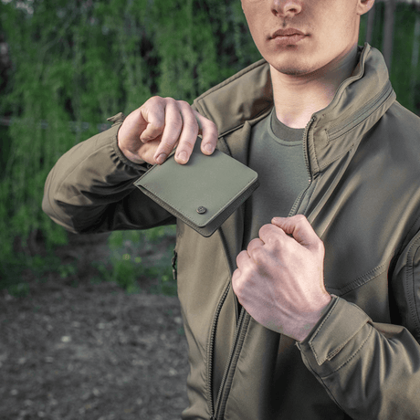Man håller M-Tac Plånbok Slim Elite Gen. II i kepsficka, kompakt design av polymerkomposit med kortfack och myntfack.