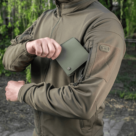 M-Tac Plånbok Slim Elite Gen. II i grön polymerkomposit hålls av person i jacka, visar kompakt design och slitstyrka.