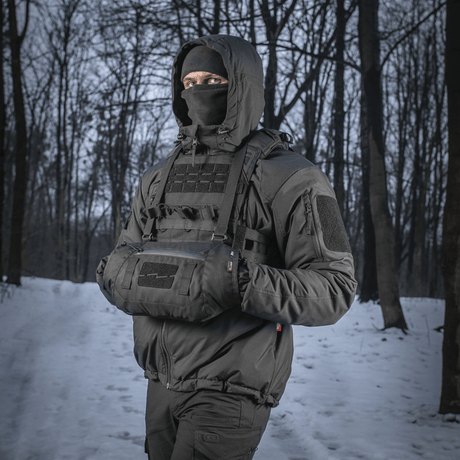 Person som bär M-Tac Taktisk Handvärmare Elite i skog med snöbakgrund, håller händerna varma i kallt väder.