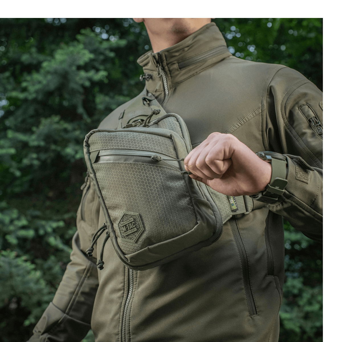 Mand med M-Tac Sling Pistoltaske Elite Hex på skulder, lavet af slidstærk Cordura 1000D, ideel til skjult våbentransport.