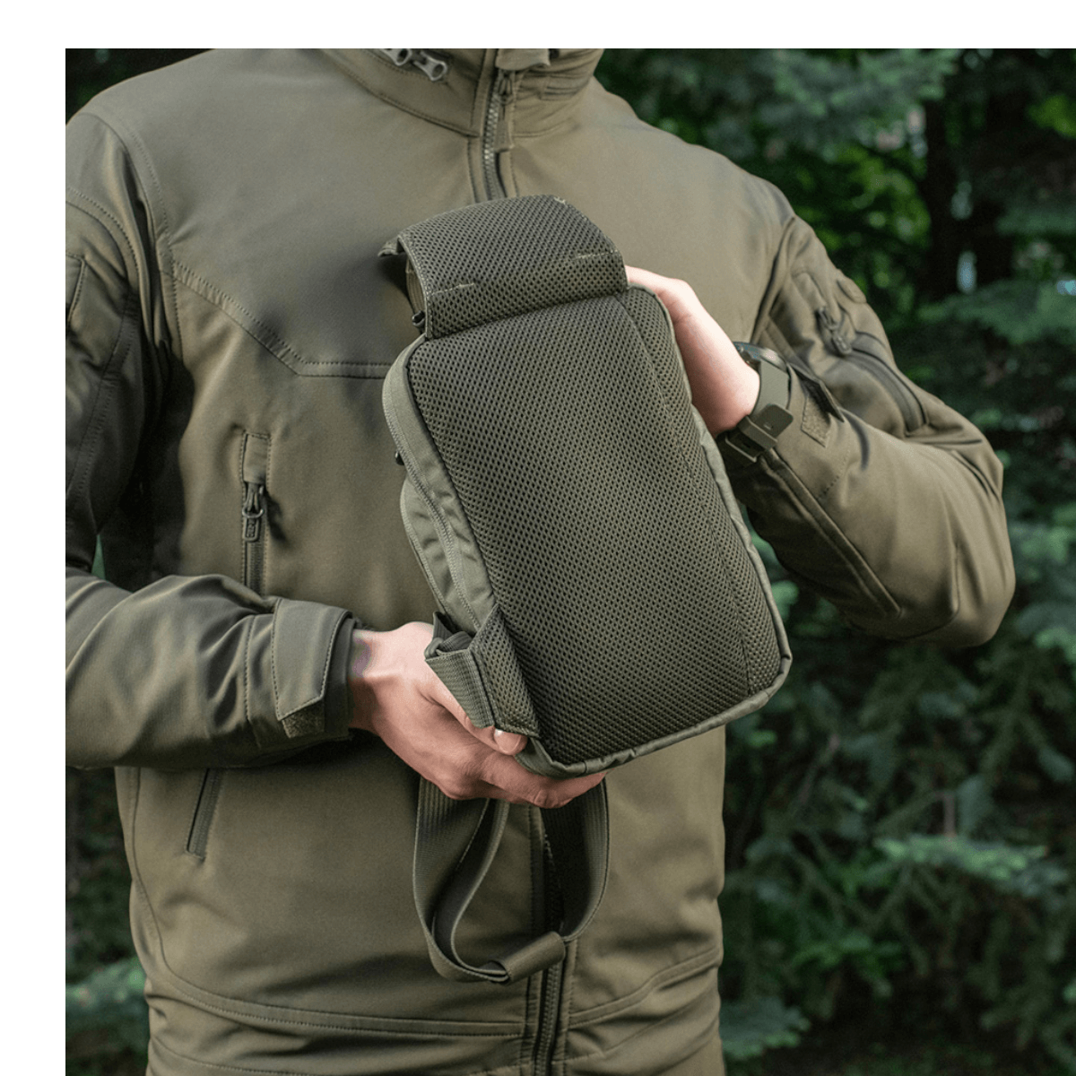 Mand holder M-Tac Sling Pistoltaske Elite Hex, lavet af holdbar Cordura, ideel til skjult våbentransport, i naturmiljø.
