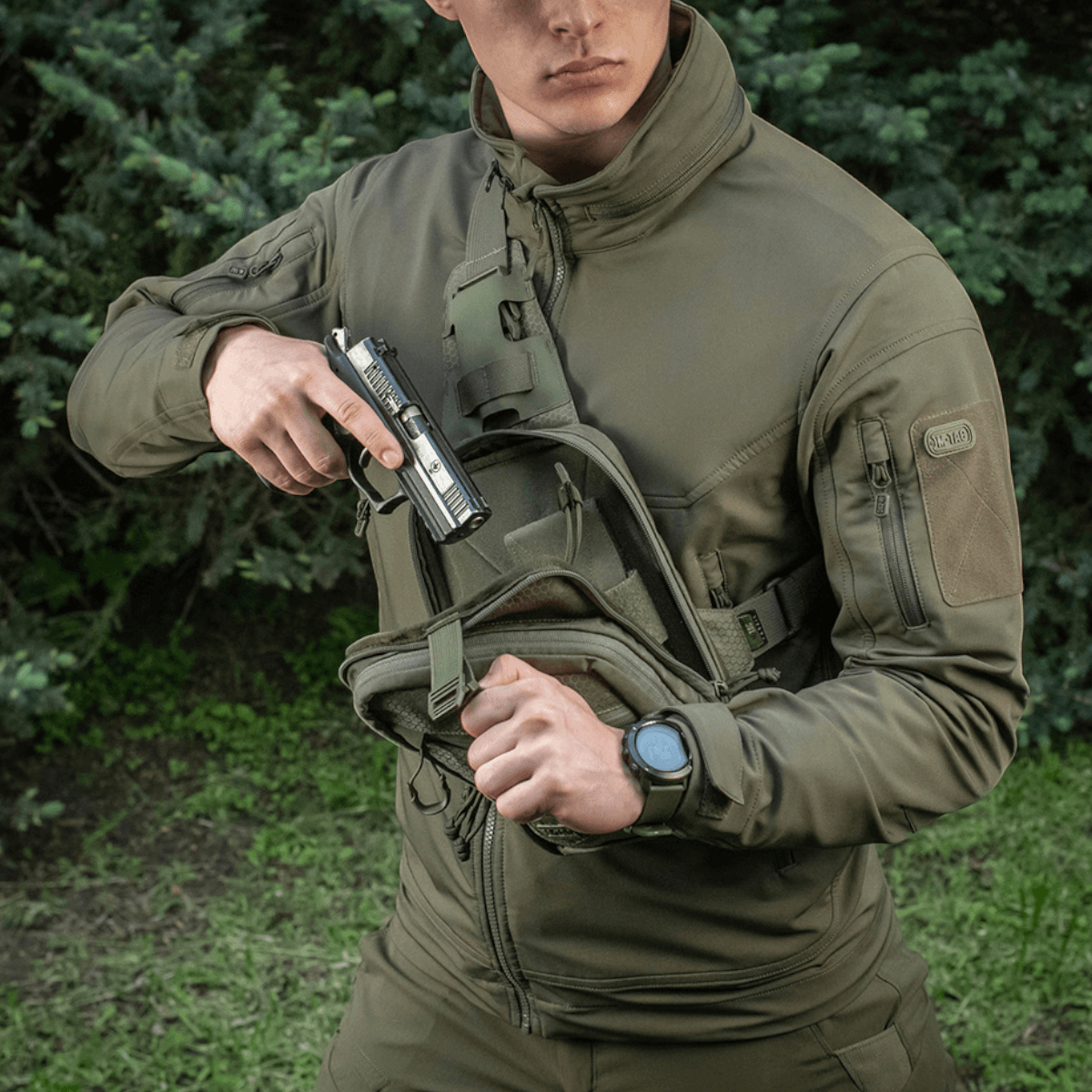 Mand iført jakke med M-Tac Sling Pistoltaske Elite Hex, praktisk til skjult våben, holdbar Cordura 1000D materiale.