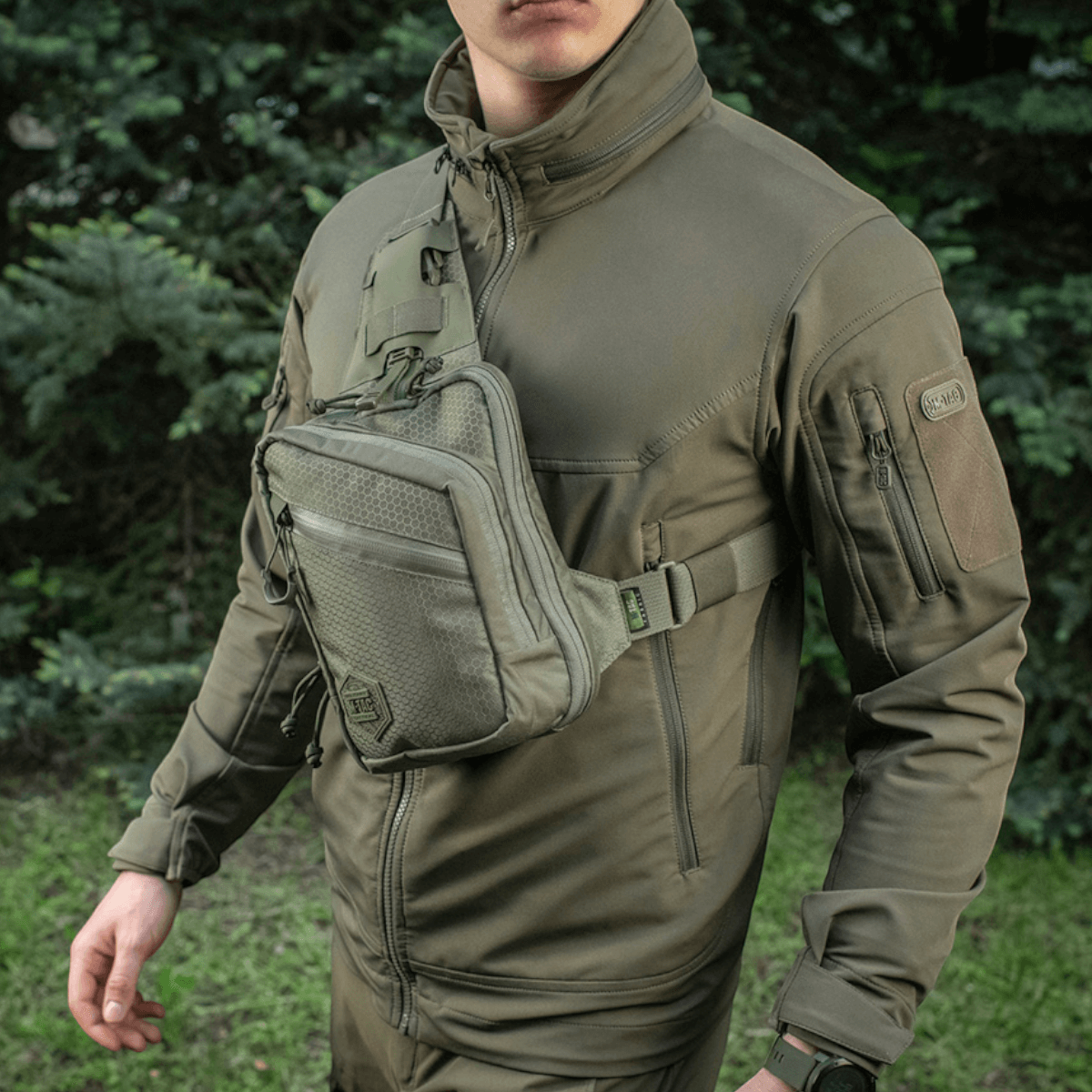 M-Tac Sling Pistoltaske Elite Hex i Cordura, bæres af person med justerbar rem i skovbaggrund
