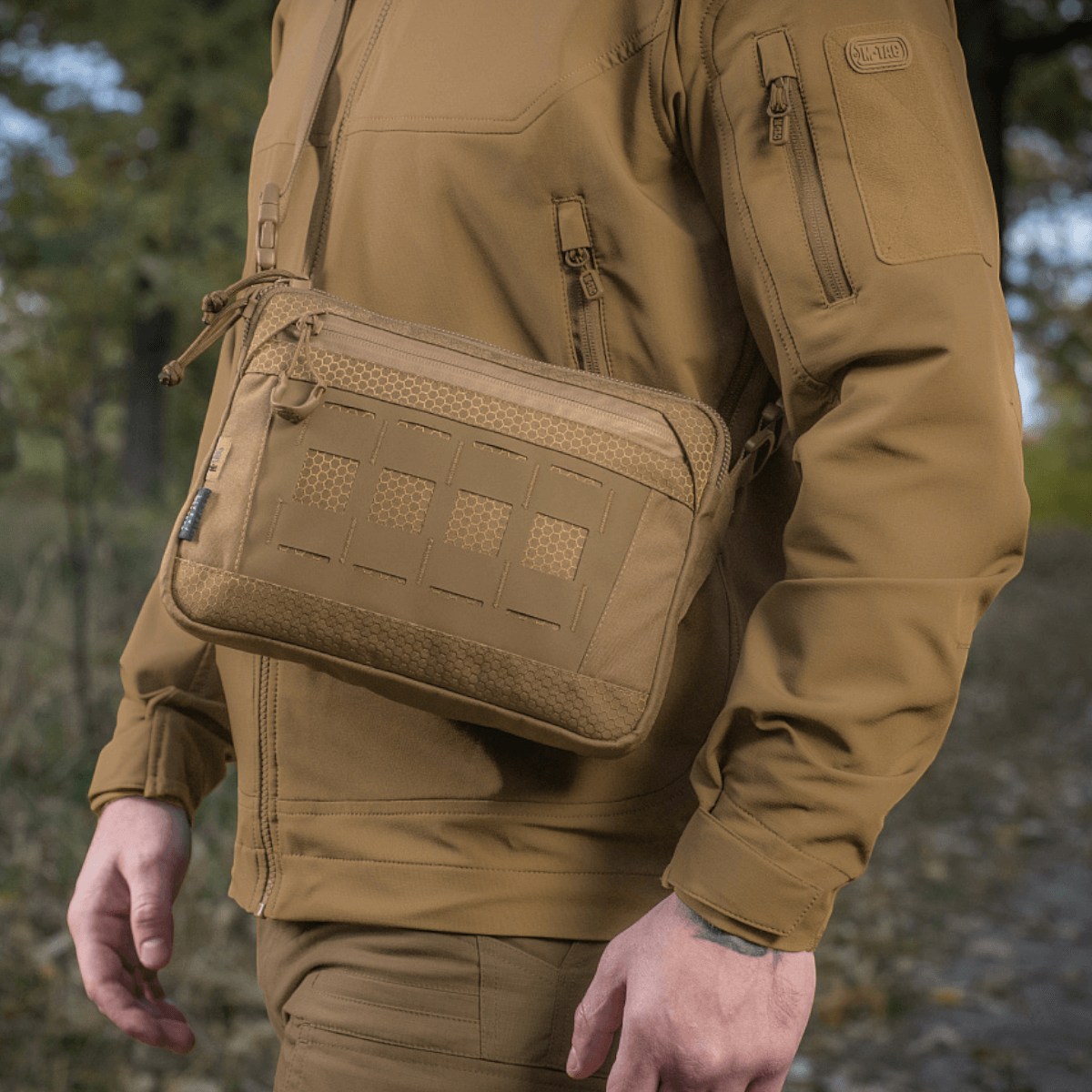 Mand bærer M-Tac Admin Taske Elite lavet af slidstærk Cordura 500D med justerbar skulderrem i naturen.