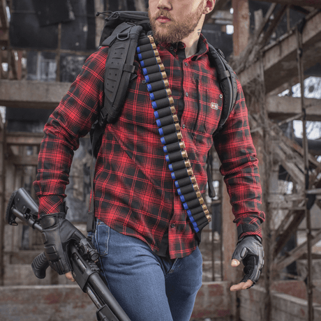 Jägare med M-Tac Bandolier Elite fylld med kaliber 12/16 patroner, redo för jakt i övergiven byggnad.