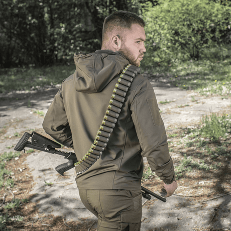 Jägare bär M-Tac Bandolier Elite med ammunition i skogsmiljö.
