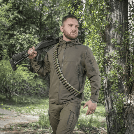 Jägare med M-Tac Bandolier Elite patronbandolier för 55 patroner, designad för snabb åtkomst till ammunition under jakt.