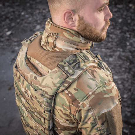 Person bär M-Tac axelkudde till Plate Carrier Cuirass QRS i camouflage med Cordura-material för komfort och hållbarhet.