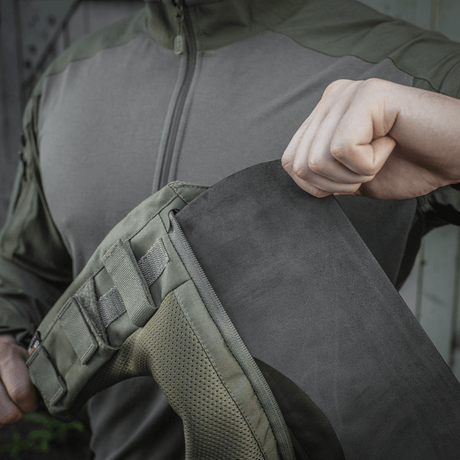 Person visar montering av M-Tac axelpad till Plate Carrier Cuirass QRS på jacka med Velcro-fäste