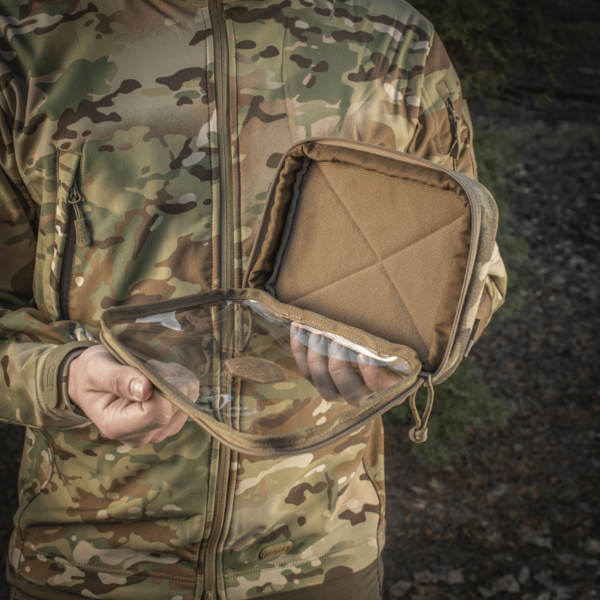 Mand holder M-Tac Utility Organizer Slim Elite med gennemsigtig forvæg og robust Cordura 500D-materiale udendørs i camouflagejakke.
