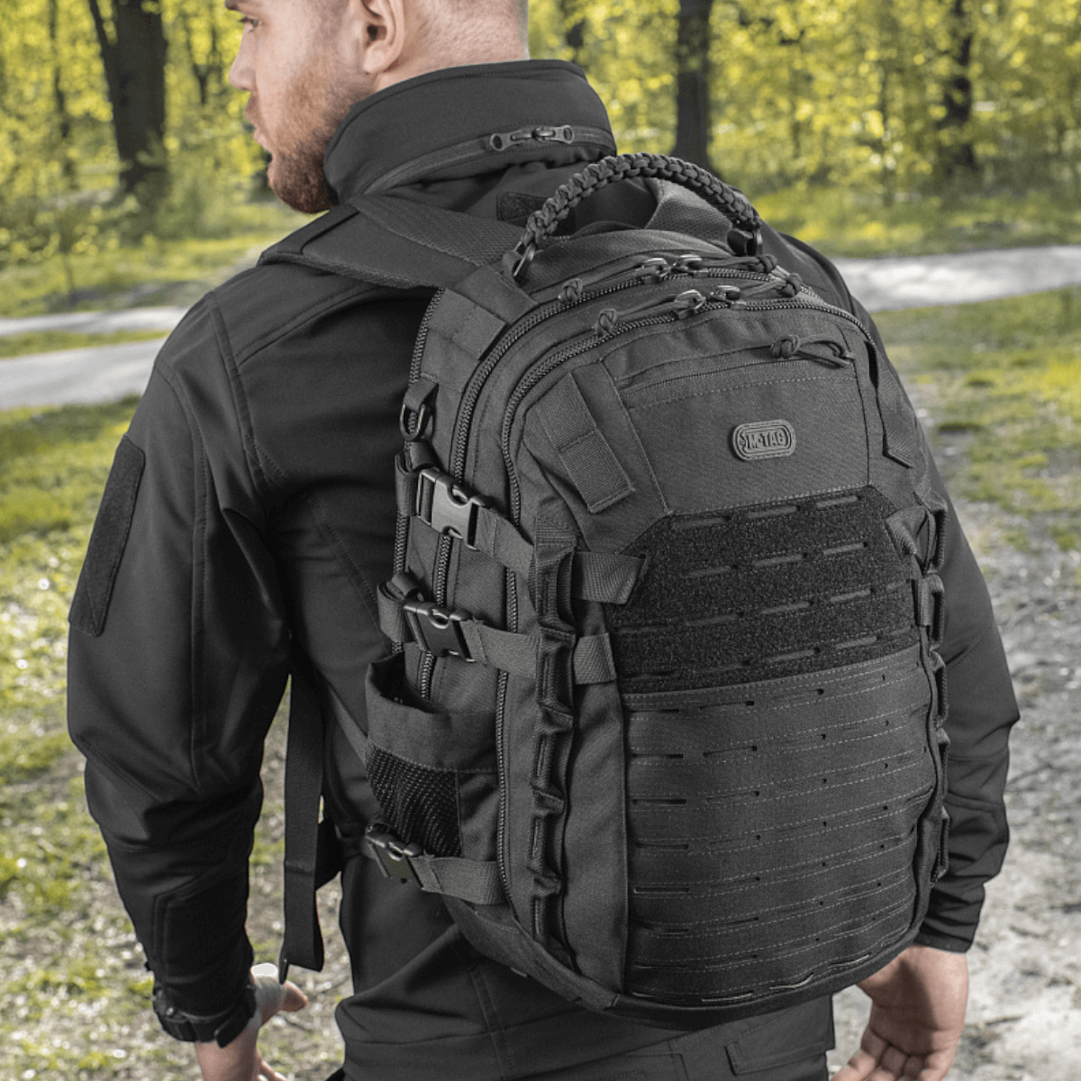 M-Tac Mission Pack Elite rygsæk i slidstærkt Cordura 1000D materiale med ergonomisk design og MOLLE LASER CUT-system på en person i outdoor-miljø.
