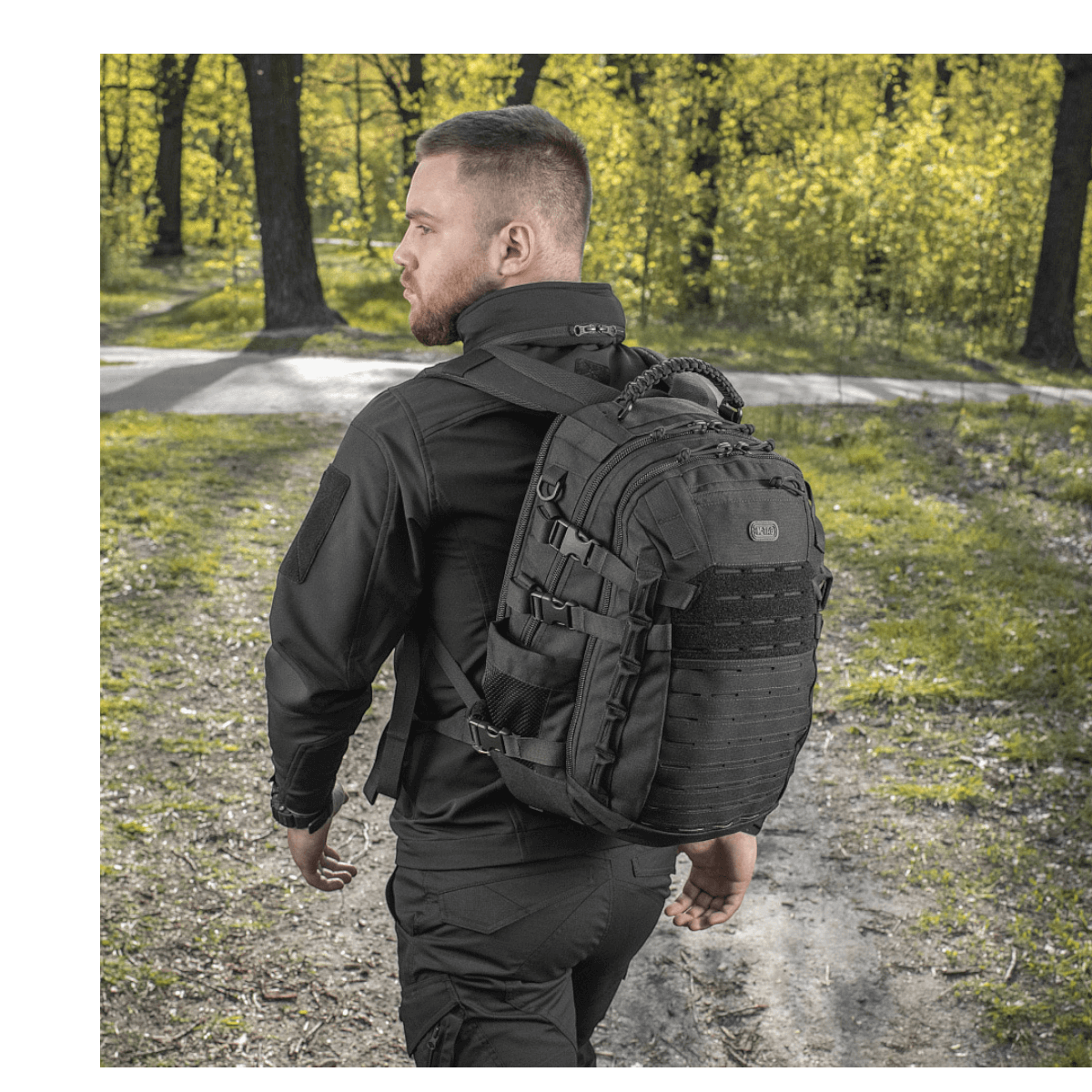 Mand bærer M-Tac Mission Pack Elite rygsæk i skovmiljø, fremstillet af slidstærkt Cordura 1000D med MOLLE LASER CUT-system.