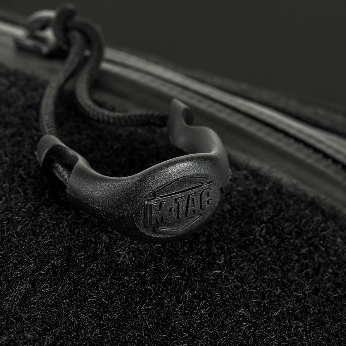 Nærbillede af YKK lynlås på M‑Tac Bæltetaske Elite Hex, der viser mærkelogoet på sort baggrund.