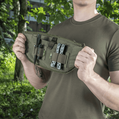 Man visar M‑Tac Bältesväska Elite Hex med verktyg, idealisk för taktisk och vardagligt bruk, tillverkad i Cordura med modulära fack.