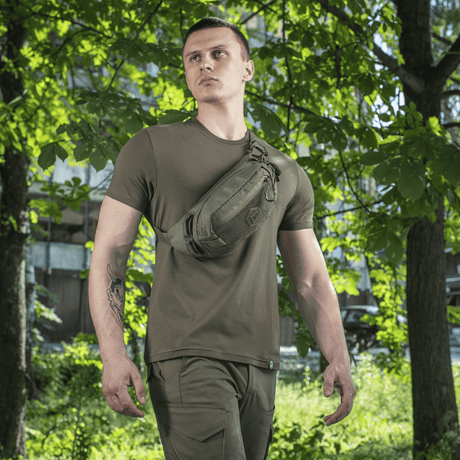 Man bär M‑Tac Bältesväska Elite Hex i naturlig miljö, idealisk för vardag, med Cordura 500D och Woojin-spännen.