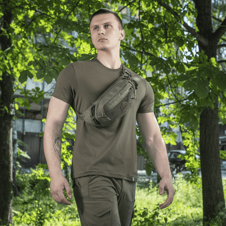 M-Tac Bältesväska Elite Hex bärs av person i naturmiljö. Väska i Cordura 500D med YKK-dragkedjor och Woojin-spännen.